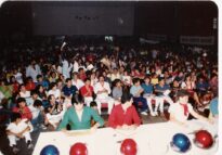 Público e pessoas à mesa durante o 12º Festival MPB de Ilha Solteira, em outubro de 1986